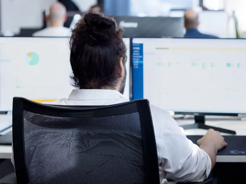 Esperto analizza i dati delle prestazioni di un sistema di intelligenza artificiale su due schermi durante un audit di maturità dell’IA