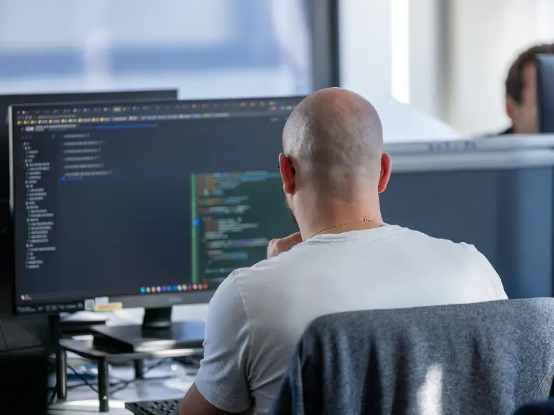 Cybersecurity expert analyzing code on a computer screen to assess potential system vulnerabilities.