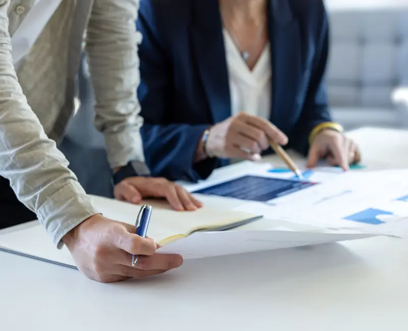 Equipo revisando documentos y datos sobre una mesa, ilustrando el análisis de expertos y la revisión de dataroom