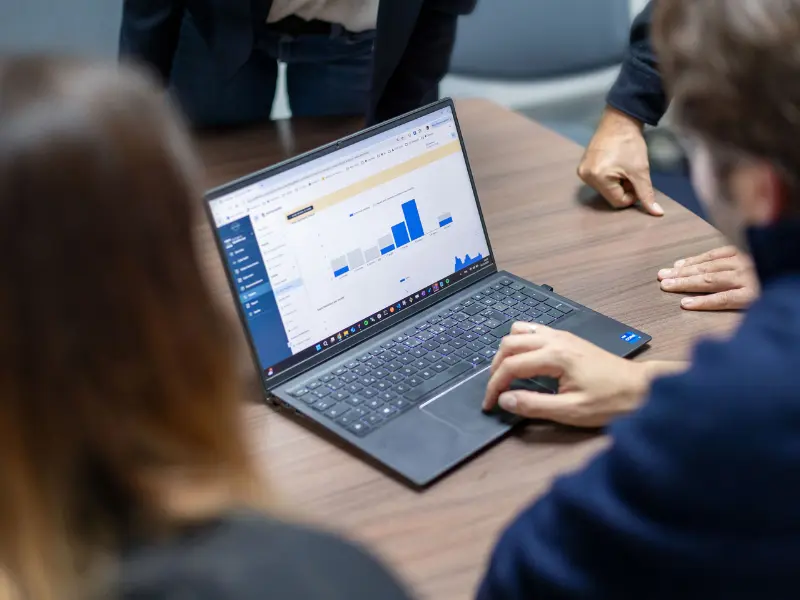 Experts reviewing AI impact data and performance charts on a laptop during an AI disruption audit