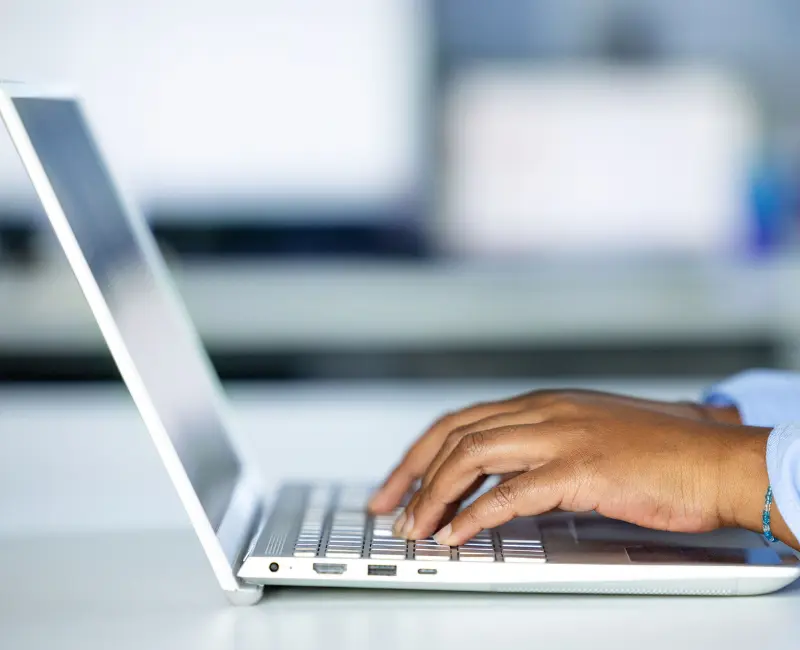 Una persona escribiendo en un ordenador portátil, ilustrando la evaluación en línea y el análisis digital.
